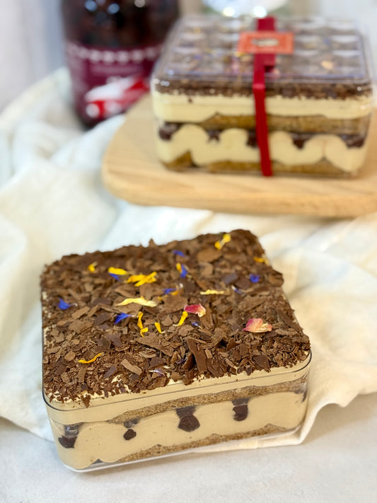 Square Oolong Tiramisu with Cherries in a box with a red ribbon on a white surface